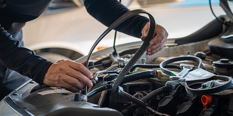 Service technician replacing car belt