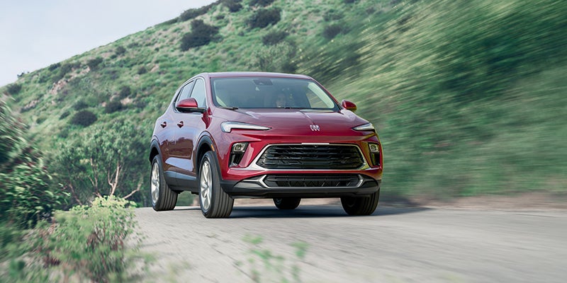 Red buick encore driving on dirty road in nature