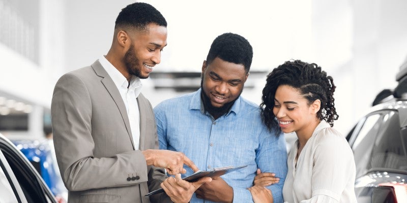 Salesman helping couple look at vehicle inventory in show room
