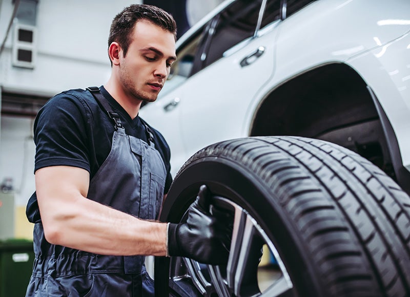 mechanic putting a tire on a car in a shop